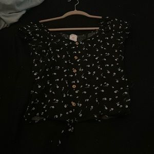 Black shirt with flower design and a little tie at the bottom.